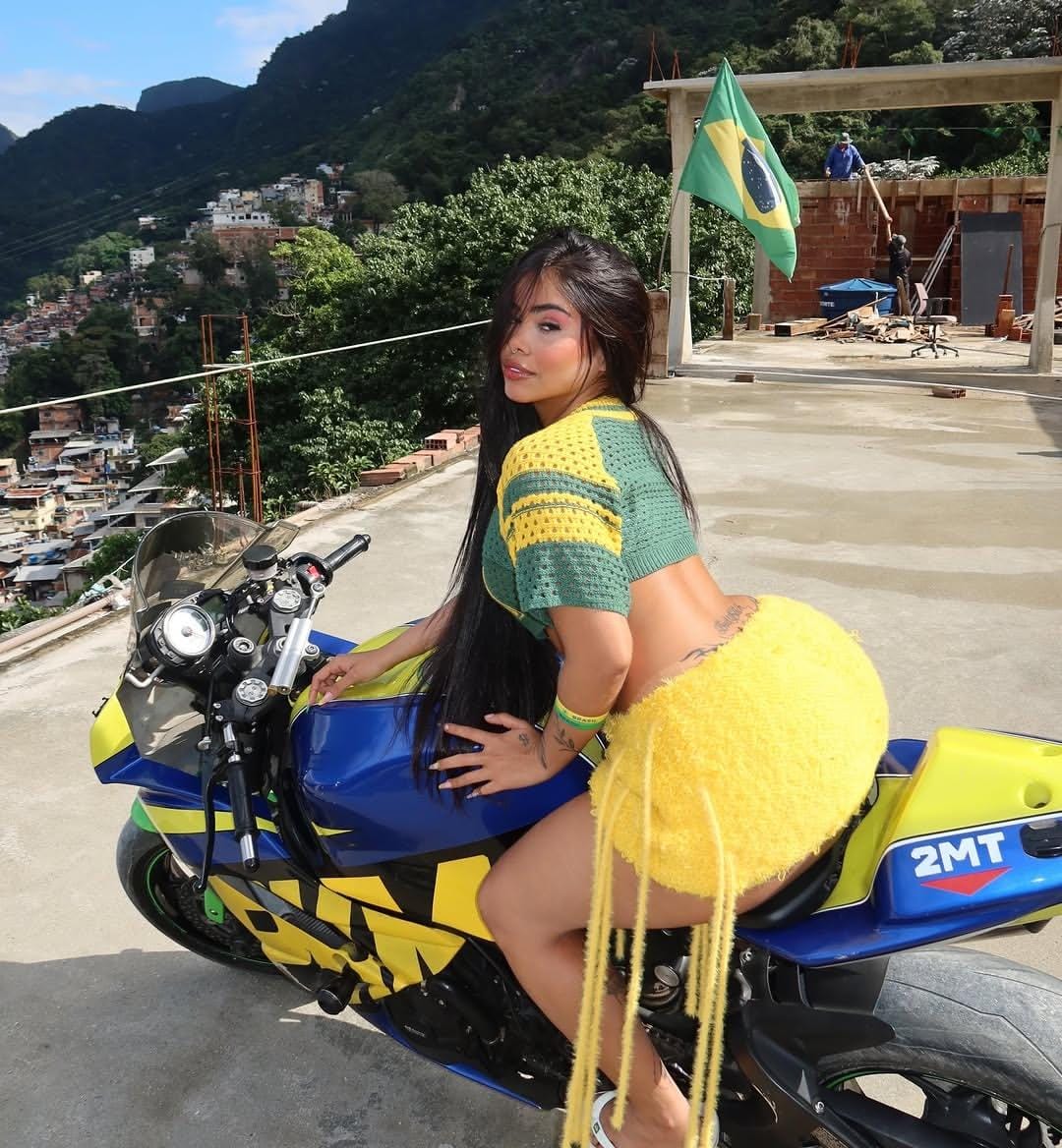 Indiaa posando de moto com bandeira do Brasil ao fundo